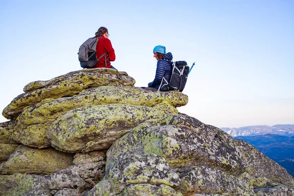 岩の上に座っている間にハイカーカップルは景色を楽しむ — ストック写真