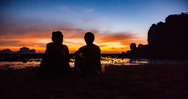 couple silhouette watching amazing sunset on the beach in Krabi