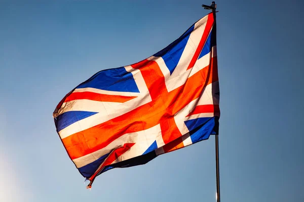 Vinker Det Forenede Kongeriges flag i den blå himmel, Union Jack flag - Stock-foto