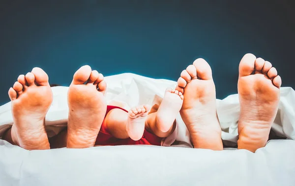 Pies de familia feliz en la cama madre padre y bebé — Foto de Stock