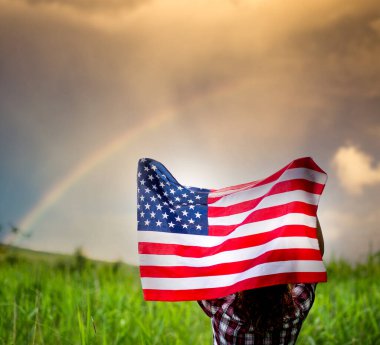 Amerikan bayrağını gökkuşağının bağımsızlık gününe karşı tutan kadın 