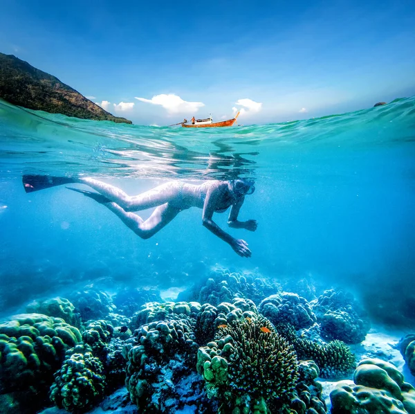 澄んだ熱帯の海でシュノーケリングをする女性 水面に水中とロングテールボートの分割イメージ アクティブな休日 — ストック写真