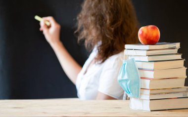 Yüzü maskeli salgın hastalıklar öğretmeni sırasında okula geri döndüm.