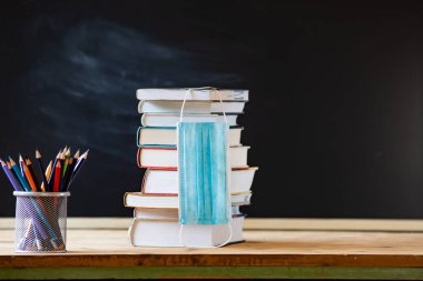 Kitap ve tıbbi maske yığını sırasında okul konseptine geri dönmek 