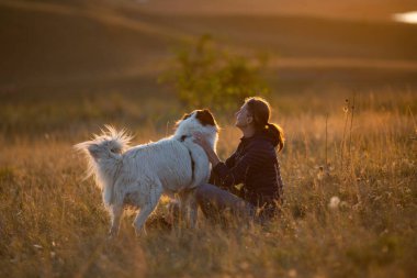 Sonbahar manzarasında beyaz köpekli mutlu bir kadın.