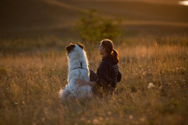 Sonbahar manzarasında beyaz köpekli mutlu bir kadın.
