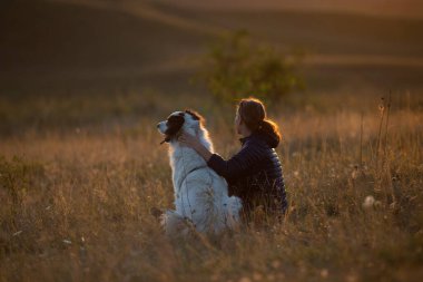 Sonbahar manzarasında beyaz köpekli mutlu bir kadın.
