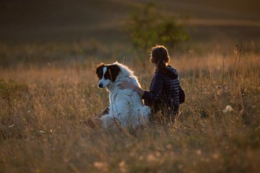 Sonbahar manzarasında beyaz köpekli mutlu bir kadın.