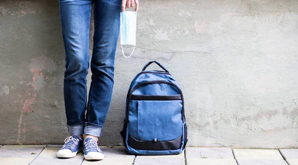 school kid feet in jeans backpack and mask back to school during pandemic