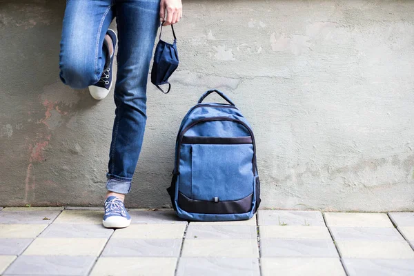 school kid feet in jeans backpack and mask back to school during pandemic