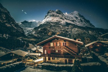 Kış gecesi Grindelwald karlı dağı, yıldızlar ve ahşap ev