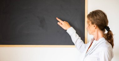 Tahtanın önünde öğretmenim.