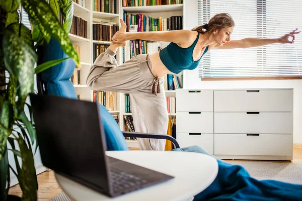 Kvinna Som Gör Yoga Asanas Hemma Med Bärbar Dator — Stockfoto