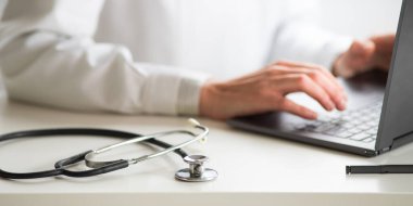 Dizüstü bilgisayar tele tıp konsepti üzerinde çalışan doktorların elleri