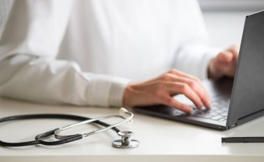 Dizüstü bilgisayar tele tıp konsepti üzerinde çalışan doktorların elleri