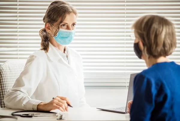 医療マスクを着用した患者に相談する女性医師 — ストック写真