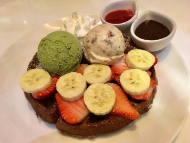 Waffle dondurma, muz, çilek ve çilek çikolata sosu ile tepesinde