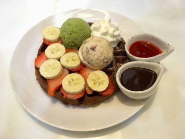 Waffle dondurma, muz, çilek ve çilek çikolata sosu ile tepesinde