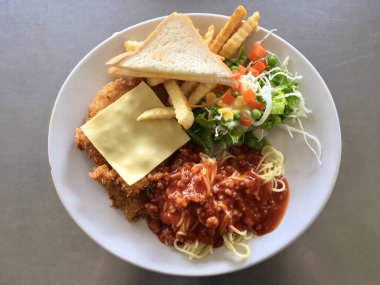 Kızarmış tavuk biftek ve domates soslu spagetti üzerine sebze salatası ve ekmek tostu.