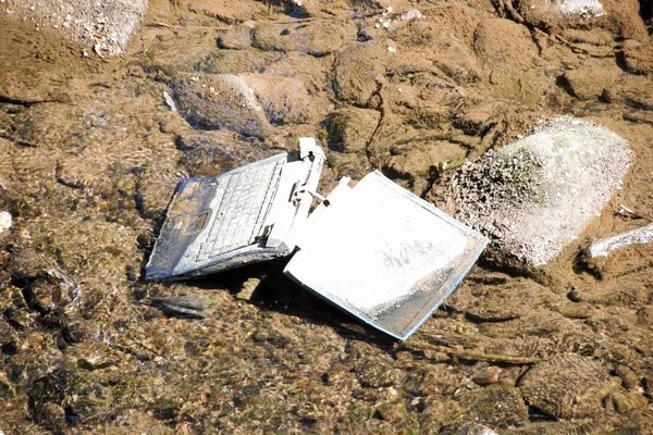 Laptop in the river /Carelessly discarded items pollute the environment and cause problems for all humanity