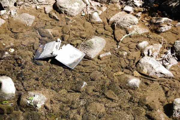 Laptop in the river /Carelessly discarded items pollute the environment and cause problems for all humanity