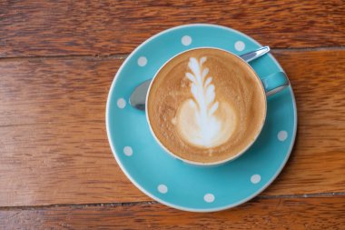 Kalp şeklinde köpük ahşap masa arka plan üzerinde beyaz bir fincan CAPUCINO veya sütlü kahve