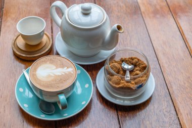 Kalp şeklinde köpük ahşap masa arka plan üzerinde beyaz bir fincan CAPUCINO veya sütlü kahve