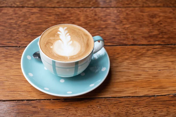 Kalp şeklinde köpük ahşap masa arka plan üzerinde beyaz bir fincan CAPUCINO veya sütlü kahve