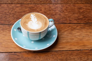 Kalp şeklinde köpük ahşap masa arka plan üzerinde beyaz bir fincan CAPUCINO veya sütlü kahve