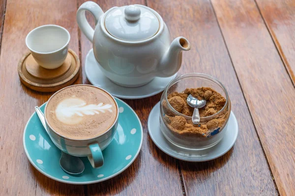 Kalp şeklinde köpük ahşap masa arka plan üzerinde beyaz bir fincan CAPUCINO veya sütlü kahve