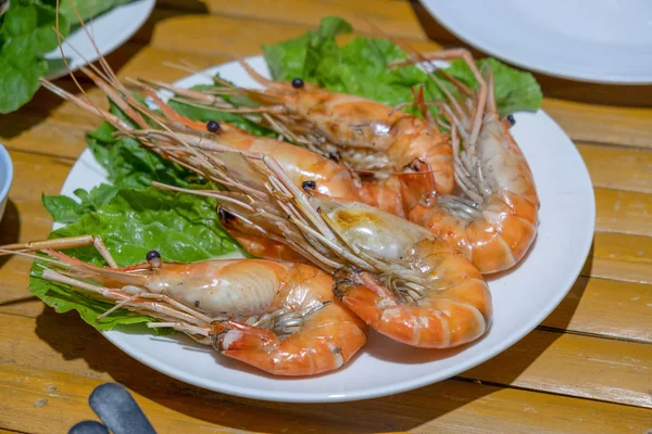 Freshly burned shrimp In a tile dish on a bamboo table and with — Stock Photo, Image