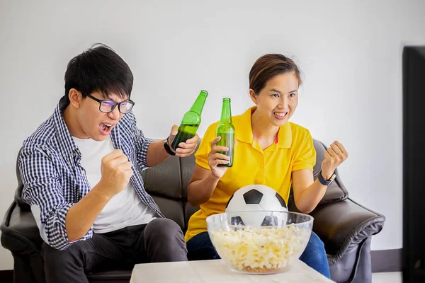 People watch soccer. Asian football supporters watching soccer on television at home with happy emotion.