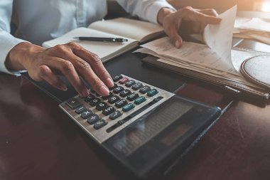 Faturaları ve hesap makinesi olan kadın. Faturaları Office masada hesaplamak için hesap makinesi kullanan kadın. Maliyetleri hesaplama.