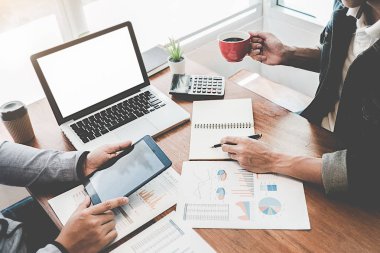 Kafesinde çalışan ve dizüstü bilgisayar kullanan genç iş adamlarının başarılı takım çalışmalarının sonuçlarını gösteren çizelge ve grafikleri ellerinde tuttukları düşünülürse....