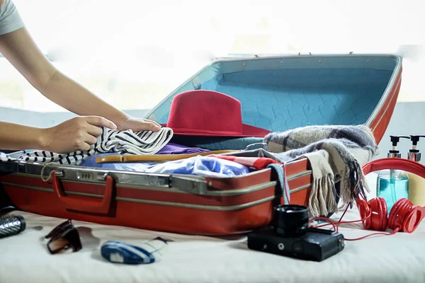 People packed suitcase with travel accessories on bed. Vacation concept