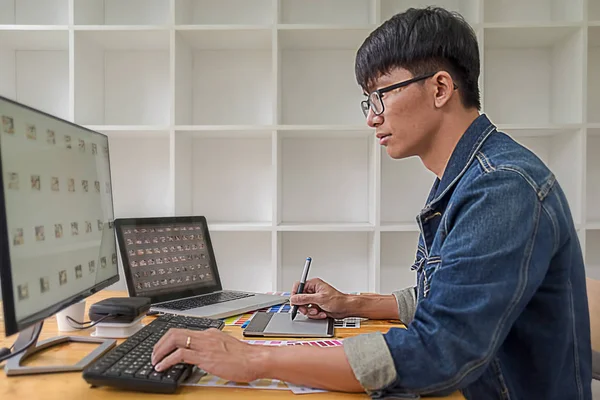 Graphic design with color swatches and tablet on a desk. Graphic designer drawing something on tablet at the office with work tools and accessories.