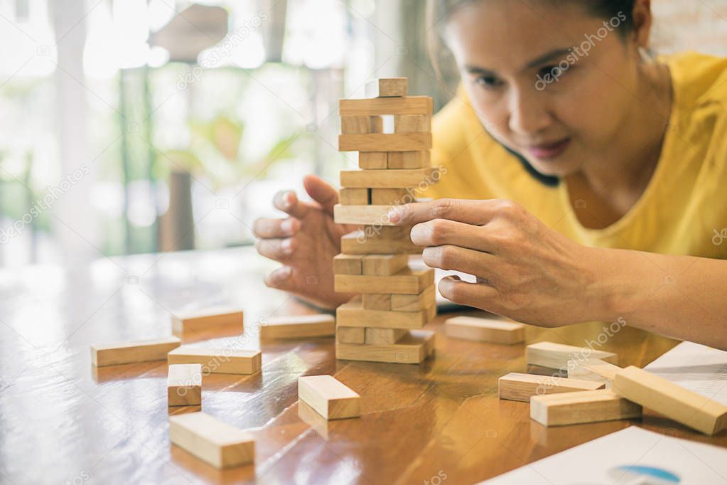 Hand of business man planning, risk and strategy in business.Businessman gambling placing wooden block on a tower.