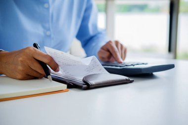 Faturaları ve hesap makinesi olan kadın. Faturaları Office masada hesaplamak için hesap makinesi kullanan kadın. Maliyetleri hesaplama.