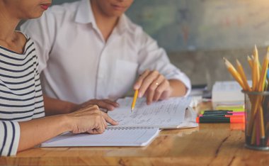 Eğitim konsepti. Öğrenciler kampüs konseptini inceliyor ve beyin fırtınası yapıyorlar. Ders kitapları ve not defterlerine yazma konularını tartışan öğrencilerin kapatılması.