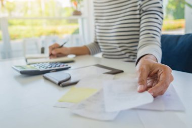 Faturaları ve hesap makinesi olan kadın. Faturaları Office masada hesaplamak için hesap makinesi kullanan kadın. Maliyetleri hesaplama.