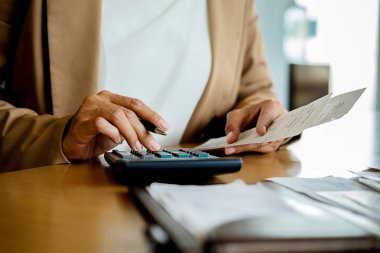Faturaları ve hesap makinesi olan kadın. Faturaları Office masada hesaplamak için hesap makinesi kullanan kadın. Maliyetleri hesaplama.
