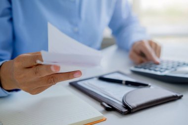 Faturaları ve hesap makinesi olan kadın. Faturaları Office masada hesaplamak için hesap makinesi kullanan kadın. Maliyetleri hesaplama.