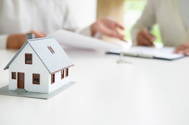 Emlakçı ve müşteri sözleşmesine satın house, sigorta ya da kredi emlak geçmişi tartışmak ile ev modeli.