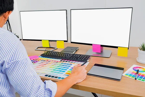 Graphic design with color swatches and tablet on a desk. Graphic designer drawing something on tablet at the office with work tools and accessories.