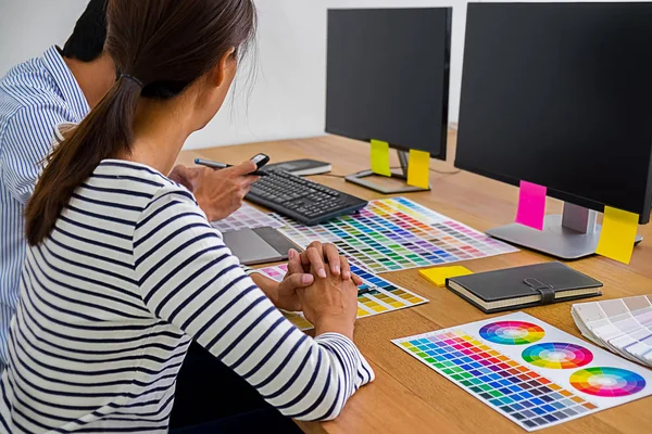 Graphic design with color swatches and tablet on a desk. Graphic designer drawing something on tablet at the office with work tools and accessories.