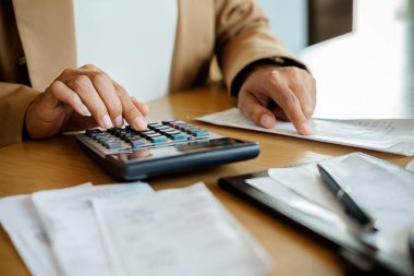 Faturaları ve hesap makinesi olan kadın. Faturaları Office masada hesaplamak için hesap makinesi kullanan kadın. Maliyetleri hesaplama.