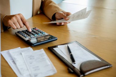Faturaları ve hesap makinesi olan kadın. Faturaları Office masada hesaplamak için hesap makinesi kullanan kadın. Maliyetleri hesaplama.