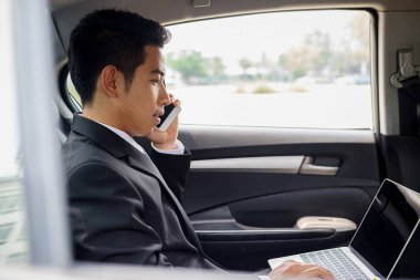 Bir arabanın arka koltuğunda oturan başarılı iş adamı