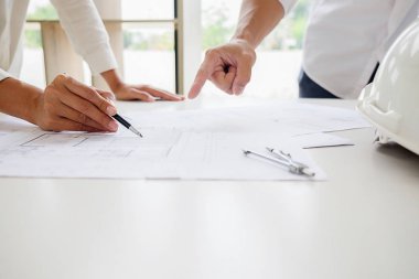 Bir ofiste bir tablet bilgisayardaki bilgileri denetlenirken bir plan mühendisleri tartışmak.