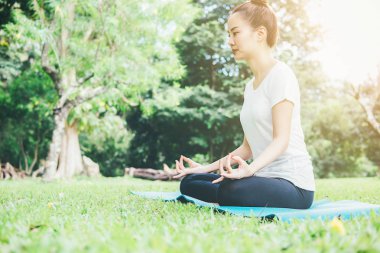 Yoga kavramı. Genç kadın ise pratik yoga Park derin derin düşünür. Sakinlik ve sakin ol, mutluluk. arka planda bulanık Bahçe